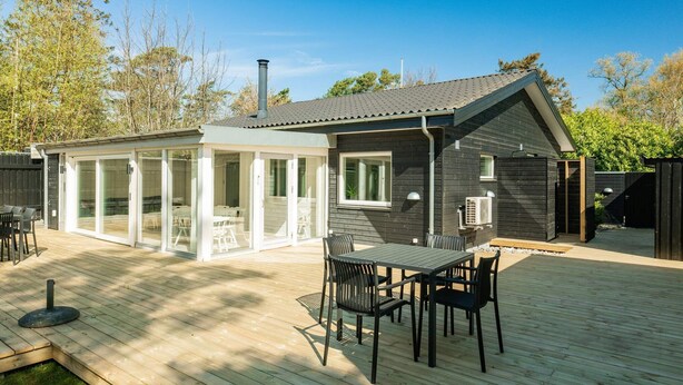 A modern house with a deck, a covered patio, and a small garden area. - 4 Star Holiday Home in Vaeggerlose (Vaeggerlose)