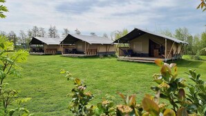 A row of three outdoor accommodation units with attached porches, set on a well-maintained lawn. - Waterfront Glamping Escape (De Veenhoop)