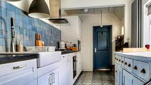 A kitchen with white cabinets, a blue tiled backsplash, and a patterned floor. - Quaint Holiday Home in Lamswaarde With Garden (Lamswaarde)