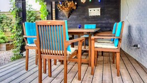 An outdoor wooden deck with a table and chairs, a hanging light fixture, and a brick wall. - Quaint Holiday Home in Lamswaarde With Garden (Lamswaarde)