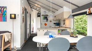 Une cuisine moderne avec des meubles blancs, un îlot central et des luminaires suspendus.
