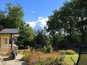 A garden with a gazebo, a grill, and a variety of flowers. - 6 Person Holiday Home in Klintehamn (Klintehamn)