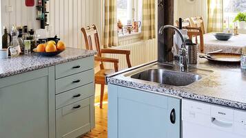 A kitchen with a granite countertop, a Bosch dishwasher, and a dining area with wooden chairs and a table.