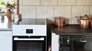 Eine Küche mit einem weißen Backofen, einer schwarzen Kochplatte und Kupferkochgeschirr.