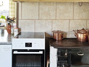 A kitchen with a white oven, a black stove, and copper cookware. - 6 Person Holiday Home in Klintehamn (Klintehamn)