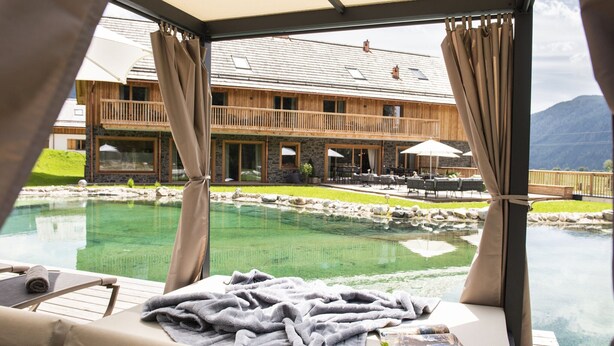 Un salon de bord de piscine offrant une vue sur un bâtiment en bois et une piscine aux eaux cristallines.