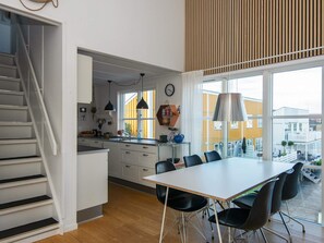 Una cocina moderna con comedor, ventanas amplias y una escalera.