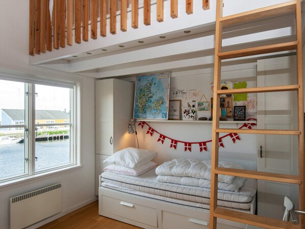 A bedroom with a bunk bed, a map on the wall, and a view of the water outside. - Cosy Holiday Apartment in Ebeltoft (Ebeltoft)