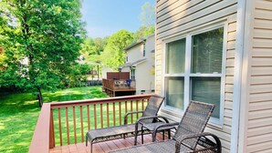 Une terrasse en bois avec des chaises en osier et une table en bois.