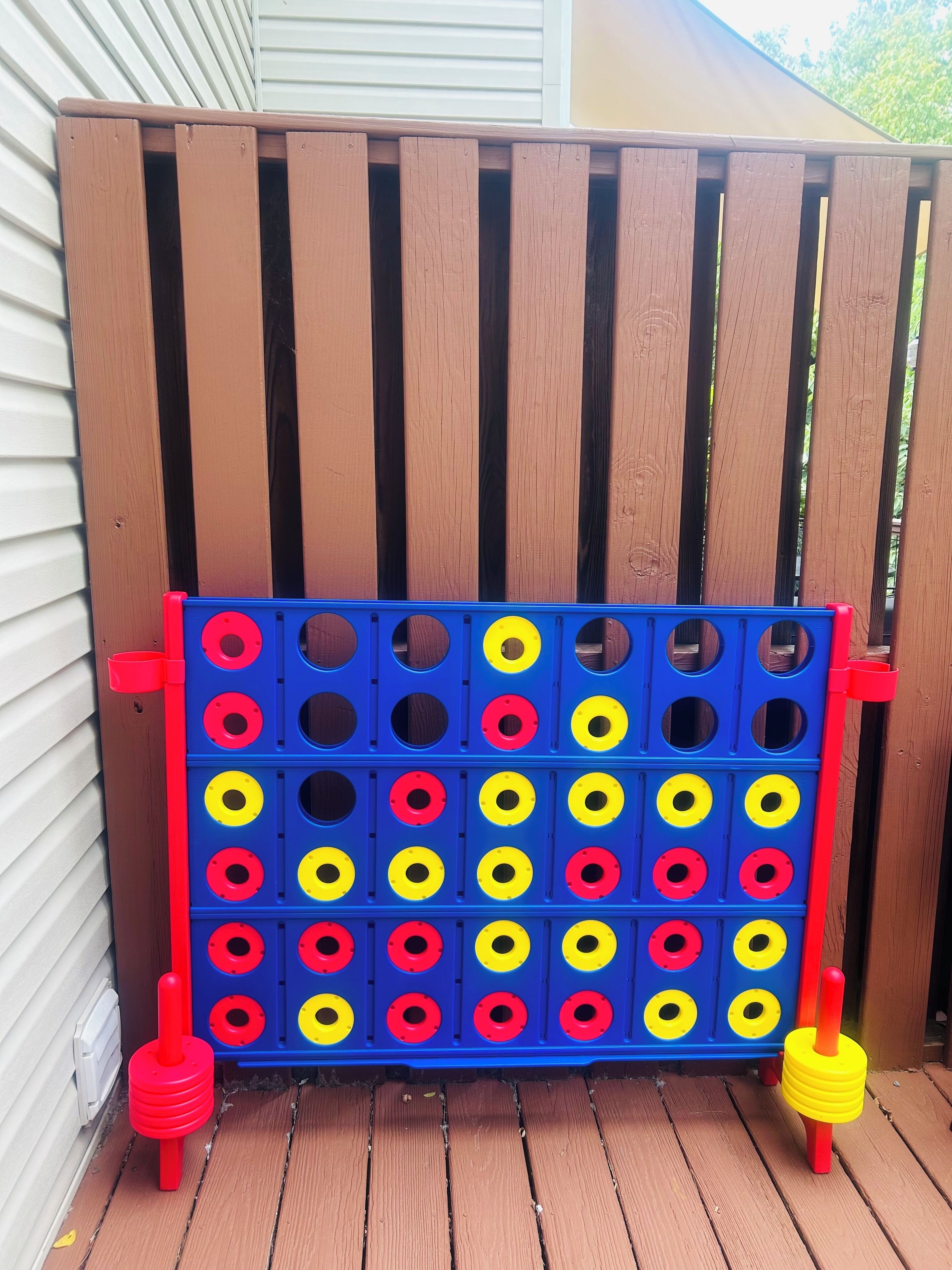 Una cerca de madera con un juego de pegboard azul y rojo.