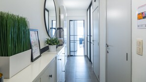 A hallway with a white counter, a potted plant, a mirror, and a door leading to a balcony. - Studio on the 3rd Floor With Phenomenal sea View (Middelkerke)