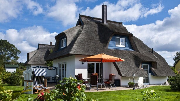 A thatched-roof house with a patio area featuring outdoor seating and a table. - Nice Apartment in Zempin (Zempin)