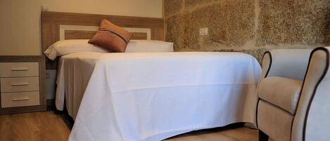 A neatly arranged bedroom with a bed, a chair, and a nightstand.