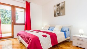 A bedroom with a bed, a nightstand, a painting, and a window with curtains. - Apartment in Croatia Near the Coast (Medulin)