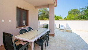 A patio with a table and chairs, a window, and a view of trees. - Apartment in Croatia Near the Coast (Medulin)