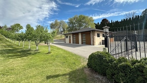 A small building with a garage, surrounded by a well-maintained lawn and trees.