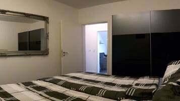 A bedroom with a bed, a wardrobe, and a mirror on the wall.