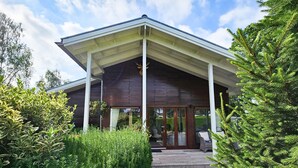 A modern house with a covered porch, large windows, and a well-maintained garden.