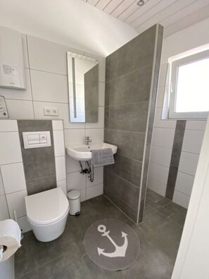 Une petite salle de bain comprenant des toilettes, un lavabo et un miroir.