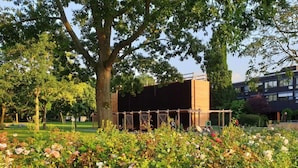 Een tuin met een houten constructie, omgeven door bloeiende planten en bomen.