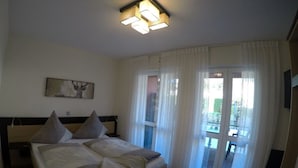 Een slaapkamer met een bed, een schilderij en uitzicht buiten door een raam.