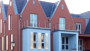 Een rij moderne huizen, rood en blauw, met schuine daken en balkons.