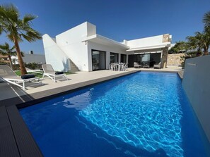 A modern house with a swimming pool, outdoor furniture, and palm trees. - Modern Villa Near Guardamar (Rojales)