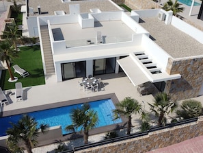A modern house with a swimming pool, outdoor seating, and a stone facade. - Modern Villa Near Guardamar (Rojales)