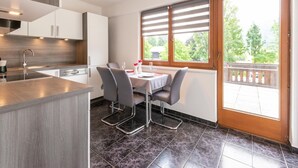 Una cocina moderna con una isla central, sillas grises y una mesa de comedor para dos.