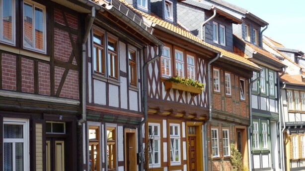 A traditional half-timbered building with a wooden door and windows, a small garden area, and a cobblestone street. - Holiday Apartment With Castle View (Wernigerode)