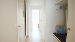 A narrow hallway with white walls and a light-colored floor, leading to a bright room at the end. - Apartment in Nieuwpoort Near the Marina (Nieuwpoort)