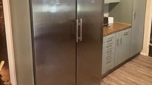 A kitchen with a stainless steel double-door refrigerator, a wooden countertop, and light-colored cabinets. - Nyhyttan Comfortable Holiday Residence (Nora)