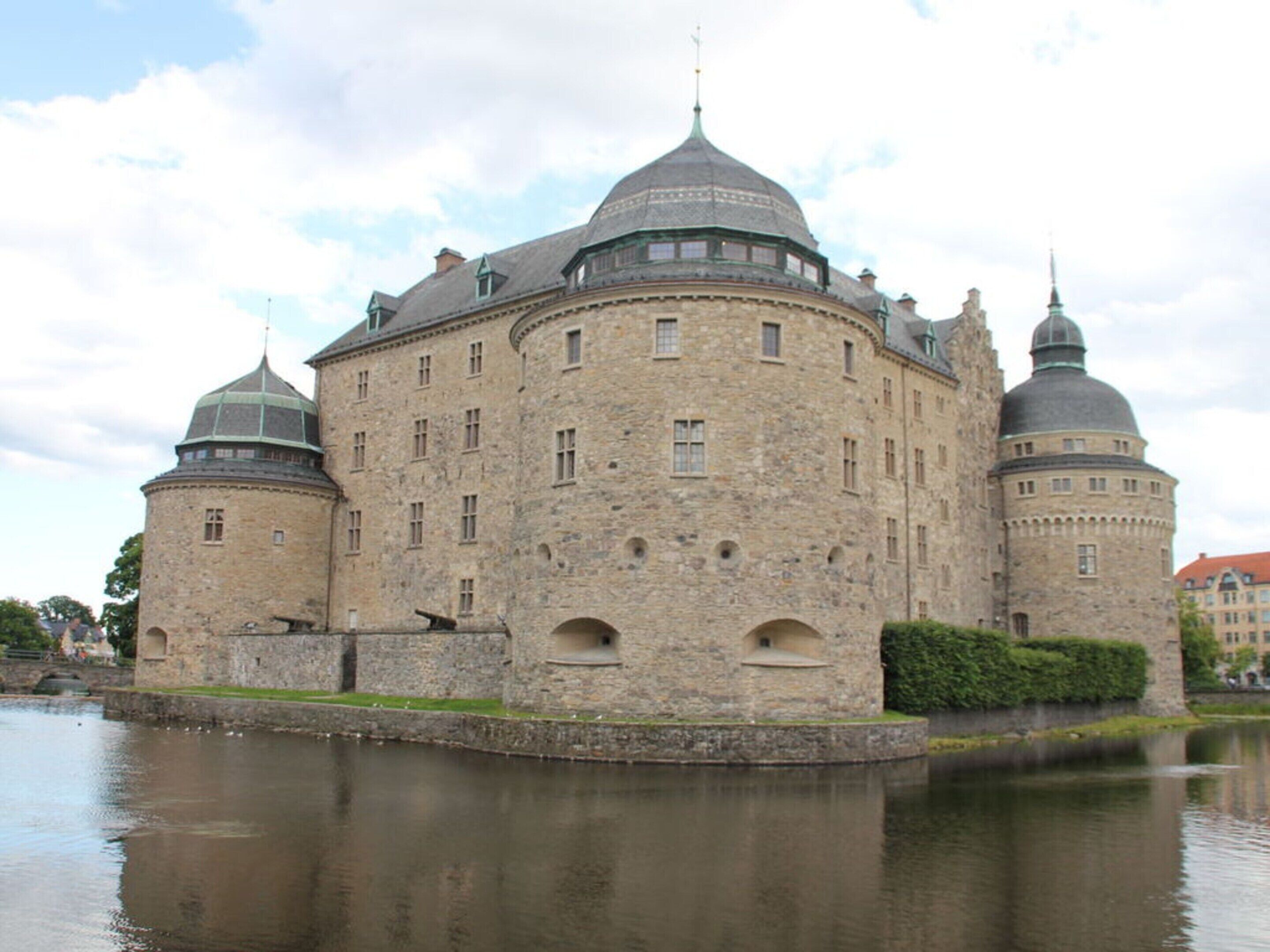 A historic stone building with multiple domes and a moat.