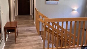 A hallway with wooden flooring, a wooden railing, and two framed pictures on the wall. - Nyhyttan Comfortable Holiday Residence (Nora)