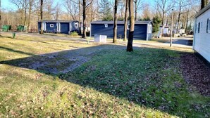 A campground with several mobile homes, a grassy area, and leaf-covered ground. - Holiday Home Chalet Drenthe (Zorgvlied)