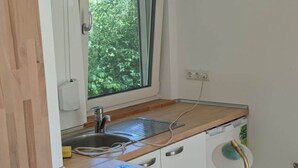 A compact kitchen with a window, a built-in dishwasher, and a stove. - Holiday Home Werder/havel (Werder (Havel))