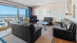 A modern living room with leather sofas, a flat-screen TV, and a dining table. - Royal 201 Seafront Apartment in a top Location (Koksijde)