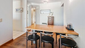 A modern kitchen with a wooden table and four black stools. There is a wooden cabinet with drawers and a small shelf. - Royal 201 Seafront Apartment in a top Location (Koksijde)