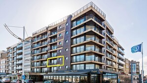 A multi-story hotel with a modern design, featuring balconies and a glass facade. - Royal 201 Seafront Apartment in a top Location (Koksijde)