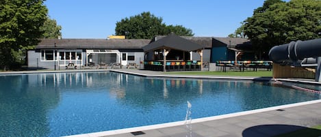 A swimming pool with a pavilion, a covered seating area, and a building with a sign that reads "Supermarket."