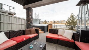Un patio al aire libre con sofás de mimbre, un jacuzzi y un pilar de piedra.