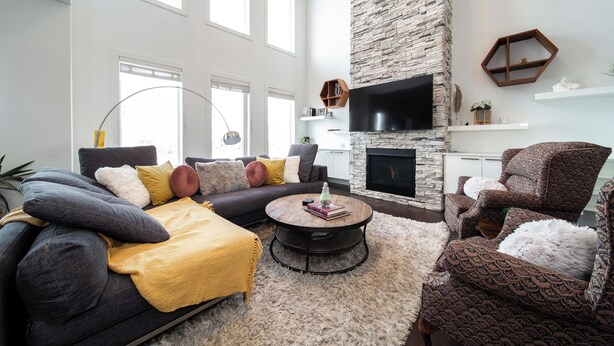 Una sala moderna con chimenea de piedra, un televisor de pantalla plana grande y una zona de estar acogedora con sofá y sillones.