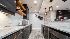 Una cocina moderna con encimeras de mármol, electrodomésticos de acero inoxidable y un suelo con patrón de espiga.