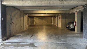 A parking garage with concrete walls, a metal roof, and a car parked on the right. - Apartment in Nieuwpoort Near Sandy Beach (Nieuwpoort)