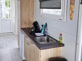 Una cocina compacta con lavavajillas integrado, cafetera y fregadero.