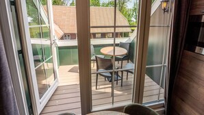 A balcony with a table and chairs, a sliding glass door, and a view of neighboring houses. - Luxury new Apartment on Ameland (Buren)