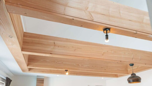 A modern kitchen with wooden beams, a built-in oven, and a hanging light fixture. - Luxury new Apartment on Ameland (Buren)