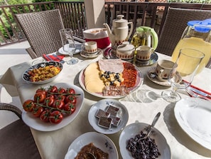 A table set for a meal with various dishes, including a plate of tomatoes, a cheese platter, and a dish of scrambled eggs. - Modern Apartment With Balcony and Garden (Konavle)