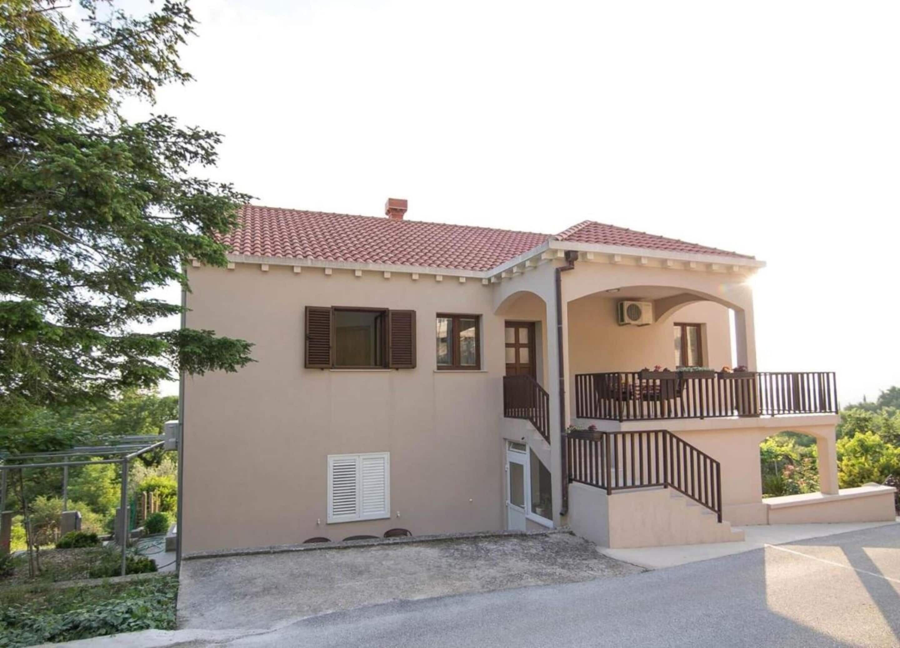 A two-story house with a balcony, a small porch, and a tiled roof.