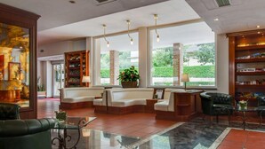A spacious lobby with a seating area, a reception desk, and a large window offering a view of greenery outside. - Apartment in Umbria With Pool and Sauna (Foligno)